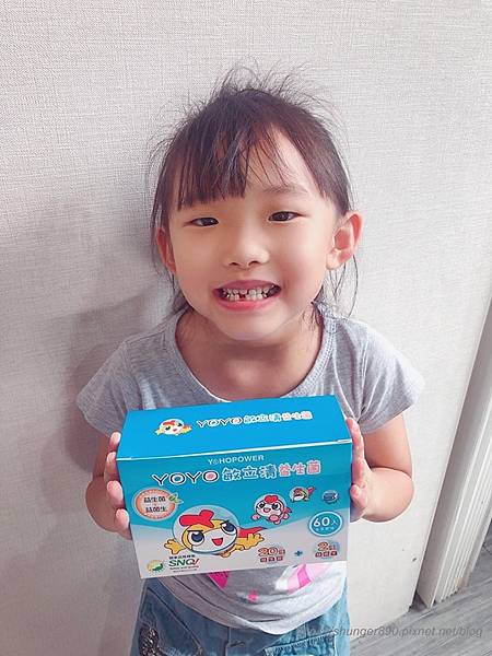 一位小女孩拿著一盒YOYO敏立清益生菌