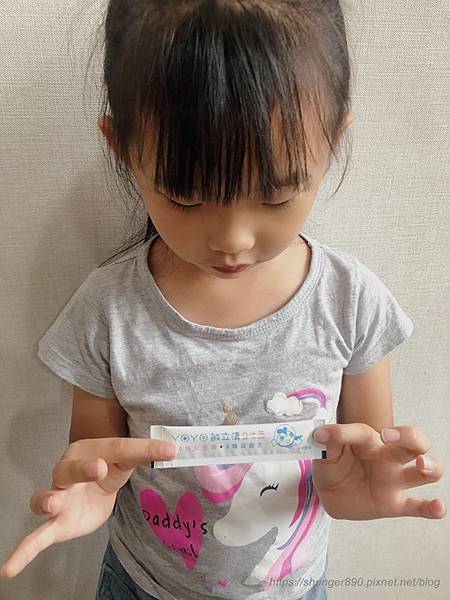 一位小女孩拿著一條YOYO敏立清益生菌