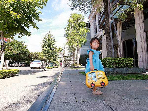 小女孩在馬路旁提著黃色書包